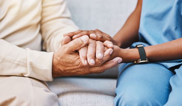 An elderly woman and her caretaker hilding hands. Nursing Home Reform in Illinois