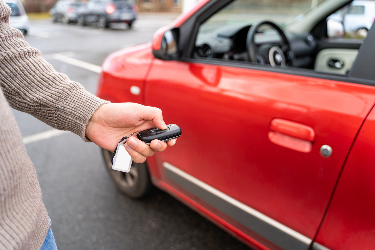 male hand holding the electronic keys of a red rental car. Joliet car accident attorney