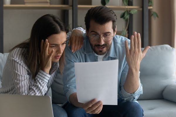 An unhappy couple receiving bad news in the mail. Can I be fired for filing a workers’ compensation claim?