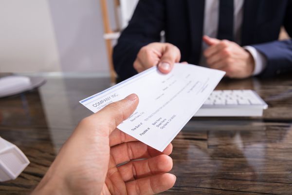 person receiving a workers compensation check after wondering how long after a workers comp settlement to get paid.