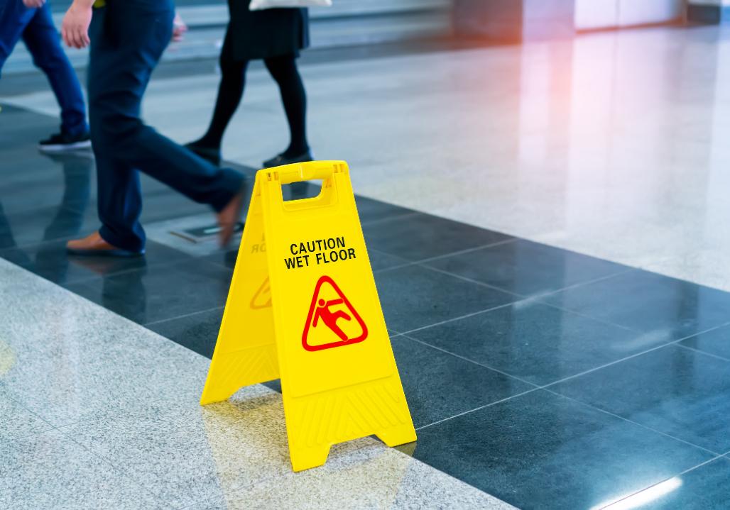 Chicago slip and fall lawyer - Caution Wet Floor placed on a slippery floor as people walk by