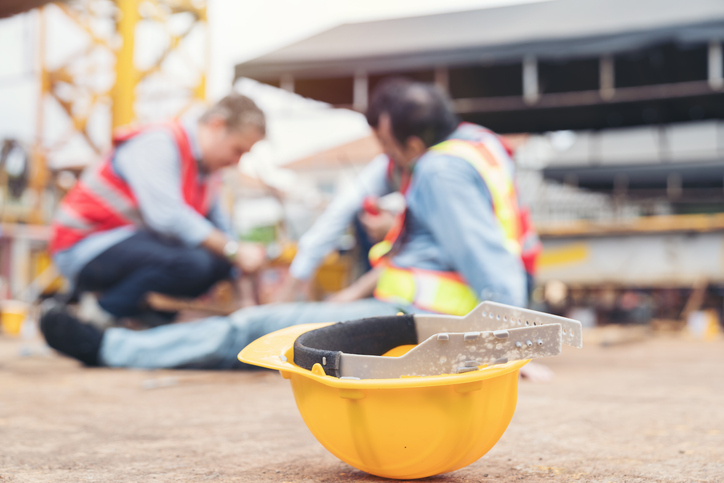 Chicago Construction Injury Lawyer - Hard hat laying on the ground beside an injured construction worker