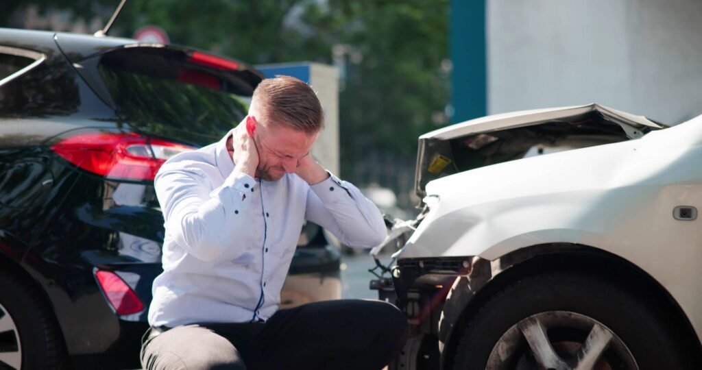 Aurora Car Accident Lawyer - Young Male Driver Seeks Legal Aid After Car Injury Whiplash.