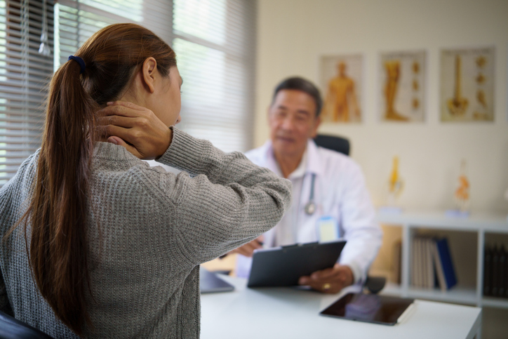 woman describing shoulder injury pain to doctor - what is the average workers' comp shoulder injury settlement?