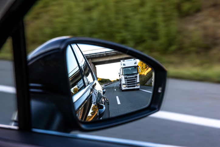 Car mirror with truck in view - How to compare truck accident lawyers in Joliet