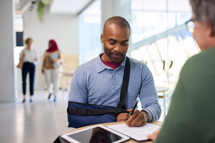 Injured man signing a form - Is workers’ compensation federal or state level?