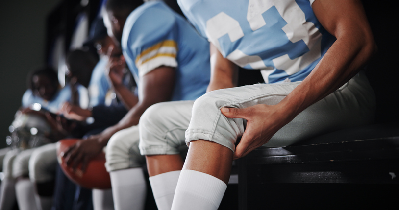 Football player holding his injured knee -Can you sue someone for a sports injury?